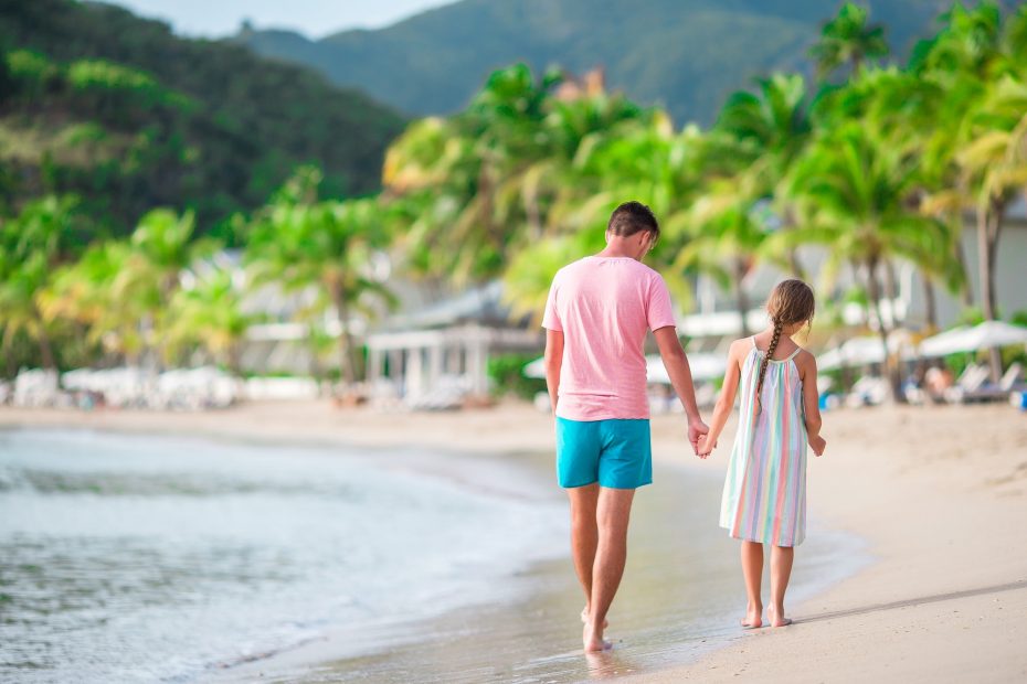 Family at tropical beach walking together on tropical Carlisle bay beach with white sand and